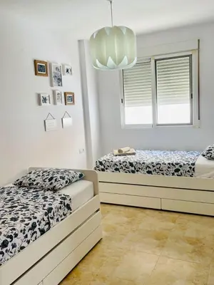 a bedroom with two beds and a chandelier at UIM Mediterraneo PB Felipe 2 Wifi in Puerto de Sagunto