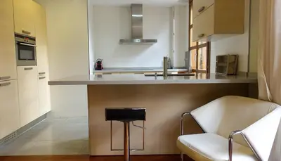 a kitchen with a counter with a stool and a chair at Moderno Apartamento en la Plaza del Tossal in Valencia