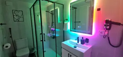 a bathroom with a sink and a shower with neon lights at A7 ViviendaTuristicaValencia Arte in Valencia