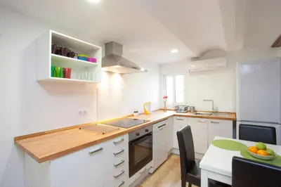 a kitchen with white cabinets and a table with a bowl of fruit at Singular Apartments Station in Valencia