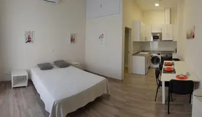 a bedroom with a white bed and a kitchen at Studio Picasso near the port and beach in Valencia