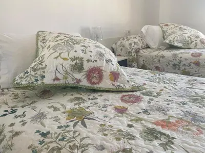 a bed with a flowered blanket and a pillow on it at Alojamiento en Losa del Obispo in Losa del Obispo