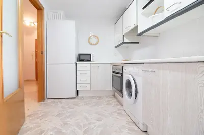 a white kitchen with a washer and dryer at Global Vacacional, Increíble apartamento en la playa, Canet d'en Berenguer in Canet de Berenguer
