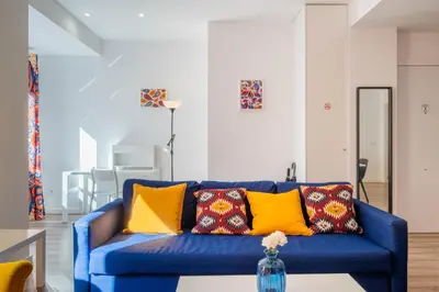 a blue couch in a living room with yellow pillows at Spacious Clean & Colorful Apt Quiet Zone in Valencia