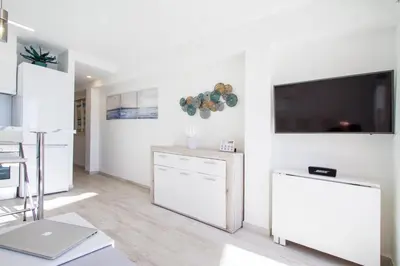 a white living room with a flat screen tv on a wall at PRIMERISIMA LINEA DE PLAYA - CULLERA BAHIA DE LOS NARANJOS I in Cullera