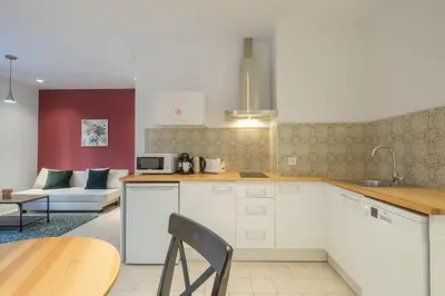 a kitchen with white cabinets and a table and a couch at Modern Apartment close to City Centre in Valencia