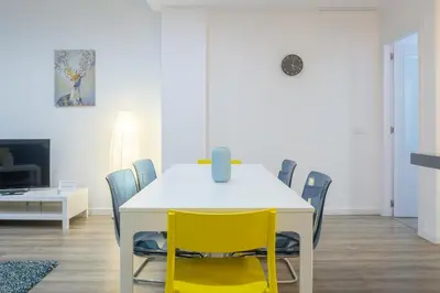 a dining room with a white table and yellow chairs at Bright, Brand new & Very Comfortable Apartment in Valencia