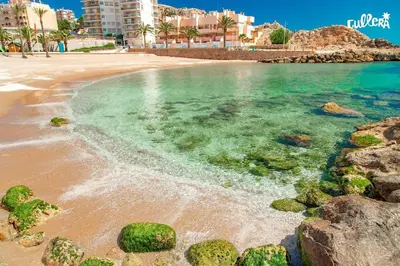 a beach with rocks in the water and buildings at Fantastico apartamento Faro de cullera a primera linea mar abierto playa de los olivos in Faro de Cullera