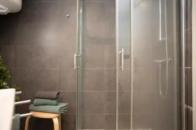 a shower with a glass door with towels on a stool at SingularStays Baleares in Valencia