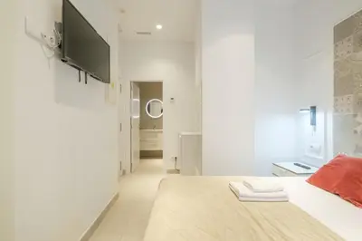 a white room with a bed and a television at Room close to City Centre in Valencia