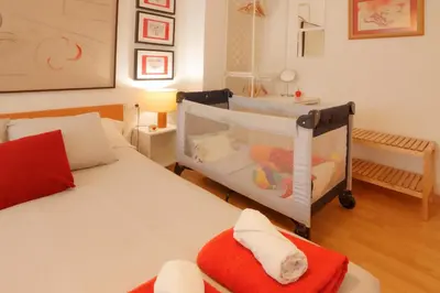 a room with two beds and a baby crib at LUMINOSO. COMODO. ACOGEDOR. WIFI. Junto a AVE in Valencia