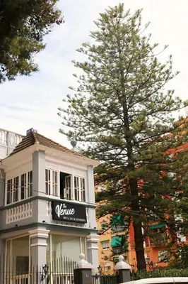 a white house with a sign on it next to a tree at The Venue Hostel Boutique in Valencia