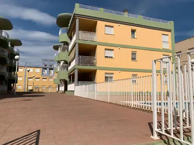 a yellow building with a fence in front of it at 3Apto con piscina en la playa cerca de VLC con AC in Puzol