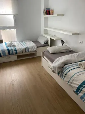 two beds in a room with wooden floors at PLAYA ALMARDA CORINTO, PISCINA, WIFI,2 TERRAZAS, BARBACOA,TRANQUILo in Sagunto