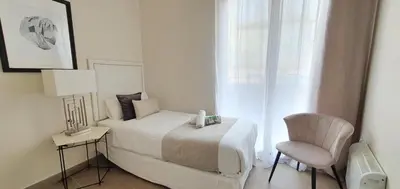 a white bedroom with a bed and a chair at Balmes Street in Valencia