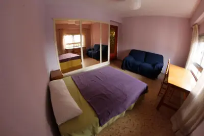 a small bedroom with a bed and a blue couch at bigger flat for holiday near beach ideal for familie with climatisacion in Valencia