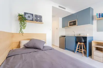 a small bedroom with a bed and a kitchen at micampus Avenida del Puerto - Residencia de Estudiantes in Valencia