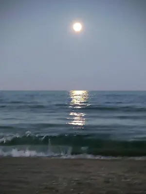 a full moon rising over the ocean with a beach at Cozy Apartment close to the beach in beatiful area in El Perelló