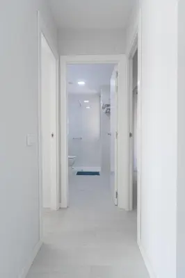 a hallway with white walls and a white bathroom at Reinapart Valencia Beach in Valencia