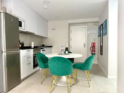 a kitchen with a white table and green chairs at Reinapart Valencia Beach in Valencia
