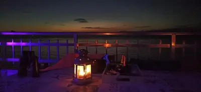 a lantern sitting on a table with the ocean at night at BLUE DOUBLE PRIVATE ROOM AT FRONT BEACH - HABITACION en la playa piso compartido in Valencia