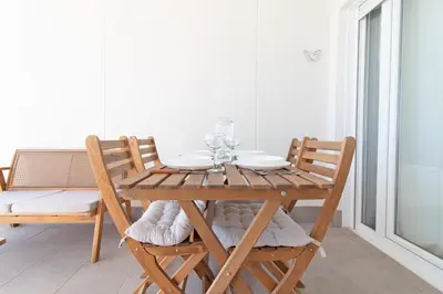 a wooden table and chairs in a room with a window at Global Vacacional, Moderno apartamento con terraza y vistas al mar in Canet de Berenguer