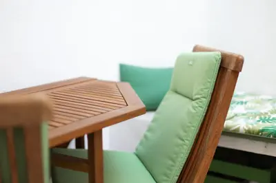 a wooden table with a green chair next to a table at Cabanyal old fisherman's house in Valencia