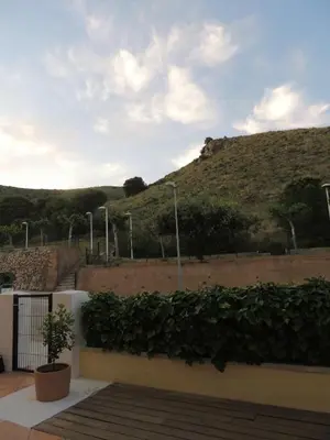 a building with a hill in the background with a plant at ACOGEDOR ADOSADO entre mar y montaña in Cullera