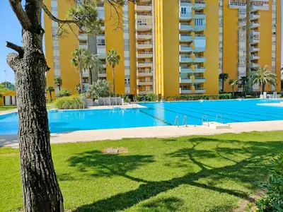 a large swimming pool with a building in the background at Global Vacacional, Practico apartamento con piscina en Residencial Brezo Canet in Canet de Berenguer