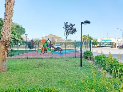 a playground with a slide in a park at Global Vacacional, Practico apartamento con piscina en Residencial Brezo Canet in Canet de Berenguer