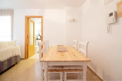a table and chairs in a room with a bedroom at Global Vacacional, Practico apartamento con piscina en Residencial Brezo Canet in Canet de Berenguer