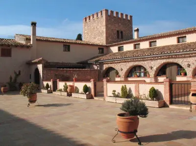 a large building with potted plants in a courtyard at MASÍA de SAN JUAN CASA NÚMERO 15 en Castillo con piscina, Aire Acondicionado y terraza privada in Segorbe