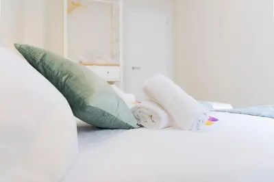 a white bed with green pillows and a towel at Cabanyal Luxury Malvarrosa Beach in Valencia