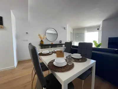 a dining room and living room with a white table and chairs at Canet De Berenguer, Playa Apto con 2 habitaciones in Valencia