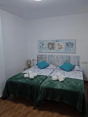 a bedroom with a bed with green sheets and blue pillows at Precioso y gran apartamento en Cullera in Cullera
