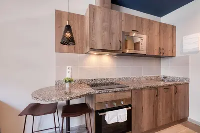 a kitchen with wooden cabinets and a counter top at Livensa Living Studios Valencia Marina Real Hotel-Apartamento in Valencia