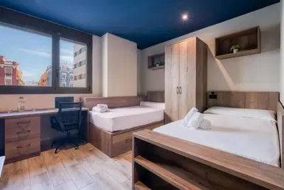 a dorm room with two beds and a desk at Livensa Living Studios Valencia Marina Real Hotel-Apartamento in Valencia