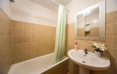 a bathroom with a sink and a mirror and a tub at 2 Bedroom Pet Friendly Home In Sagunto in Sagunto