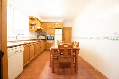 a kitchen with wooden cabinets and a table and chairs at Global Vacacional, Bonita casa rural en Quart de les Valls in Cuart de les Valls