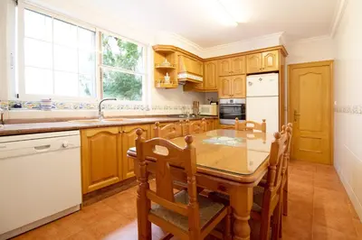 a kitchen with wooden cabinets and a wooden table and chairs at Global Vacacional, Bonita casa rural en Quart de les Valls in Cuart de les Valls