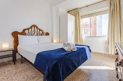 a bedroom with a bed with a blue blanket and a window at Town center Apartment El Perello Valencia in El Perelló