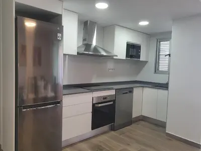 a kitchen with white cabinets and a stainless steel refrigerator at SingularStays Cullera IV in Cullera