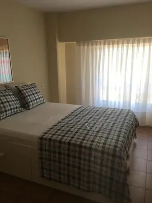 a bedroom with a bed with a plaid blanket and a window at MAGNO CULLERA- Playa in Cullera