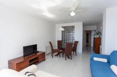 a living room with a blue couch and a dining room at Cullera Apartment Faro in Cullera
