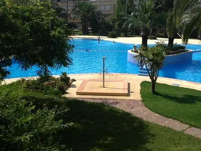 a large blue swimming pool with people swimming in it at Jamaica Beach House in Puebla de Farnals