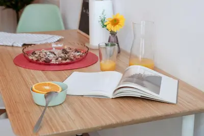 a table with a book and a bowl of food and orange juice at NB - Cozy loft steps from City of Arts & Sciences in Valencia
