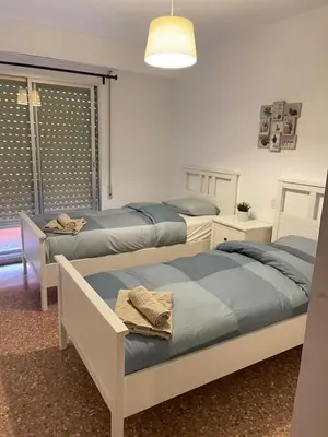 a bedroom with two beds and a window with a lamp at UIM Mediterraneo Isabel 23 Wifi in Puerto de Sagunto