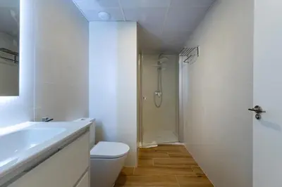 a white bathroom with a toilet and a shower at Travel Habitat Alameda Suites. in Valencia