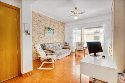 a living room with a couch and a table with a television at Relax Les Palmeres in Sueca