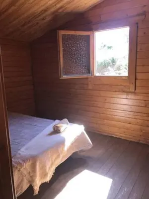 a room with a bed in a wooden cabin with a window at Retiro Siete Aguas in Siete Aguas
